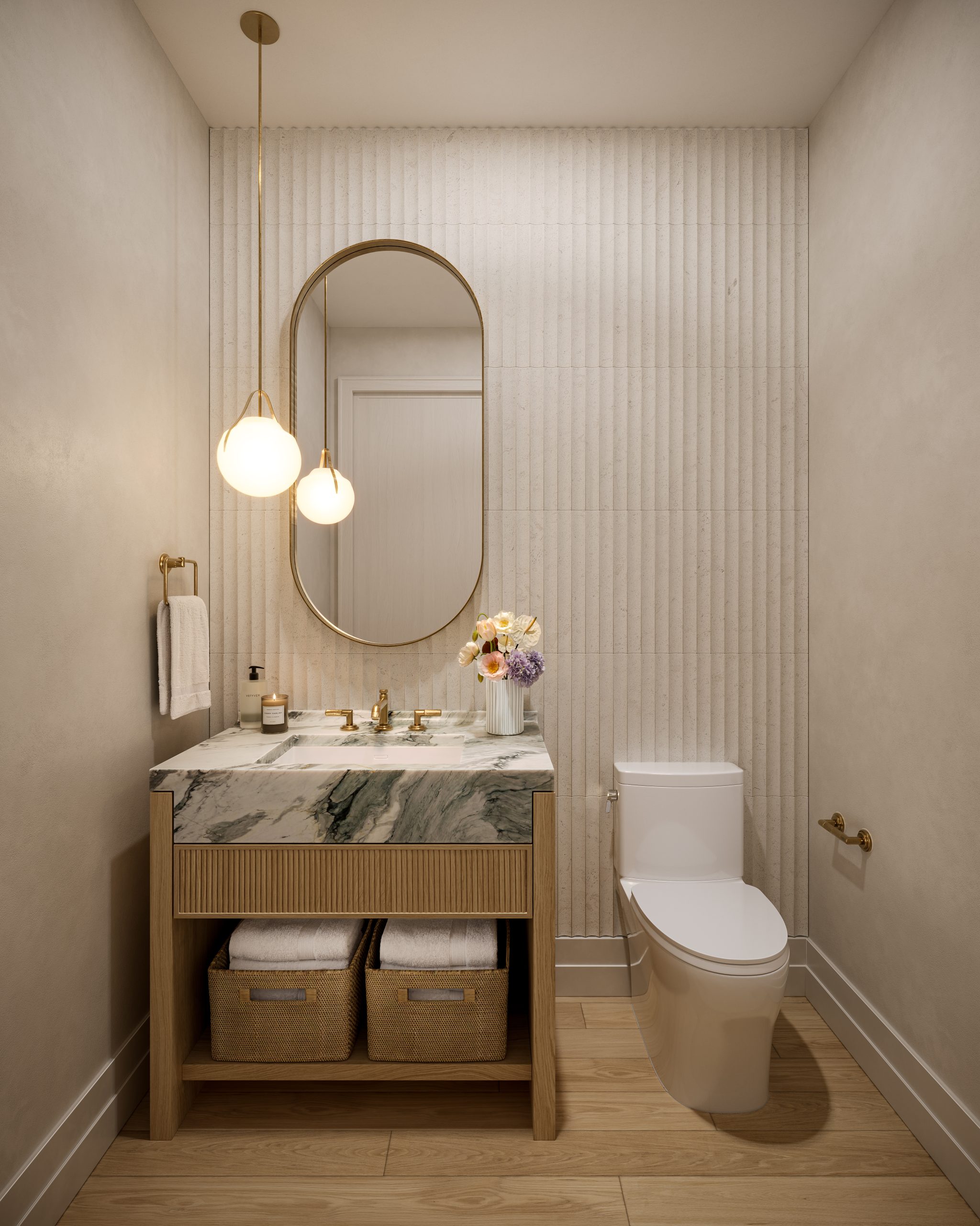 Powder room with fluted pale walls, an oak vanity with a green-veined marble top and woven baskets below, a pill-shaped mirror and two globe pendant lights.