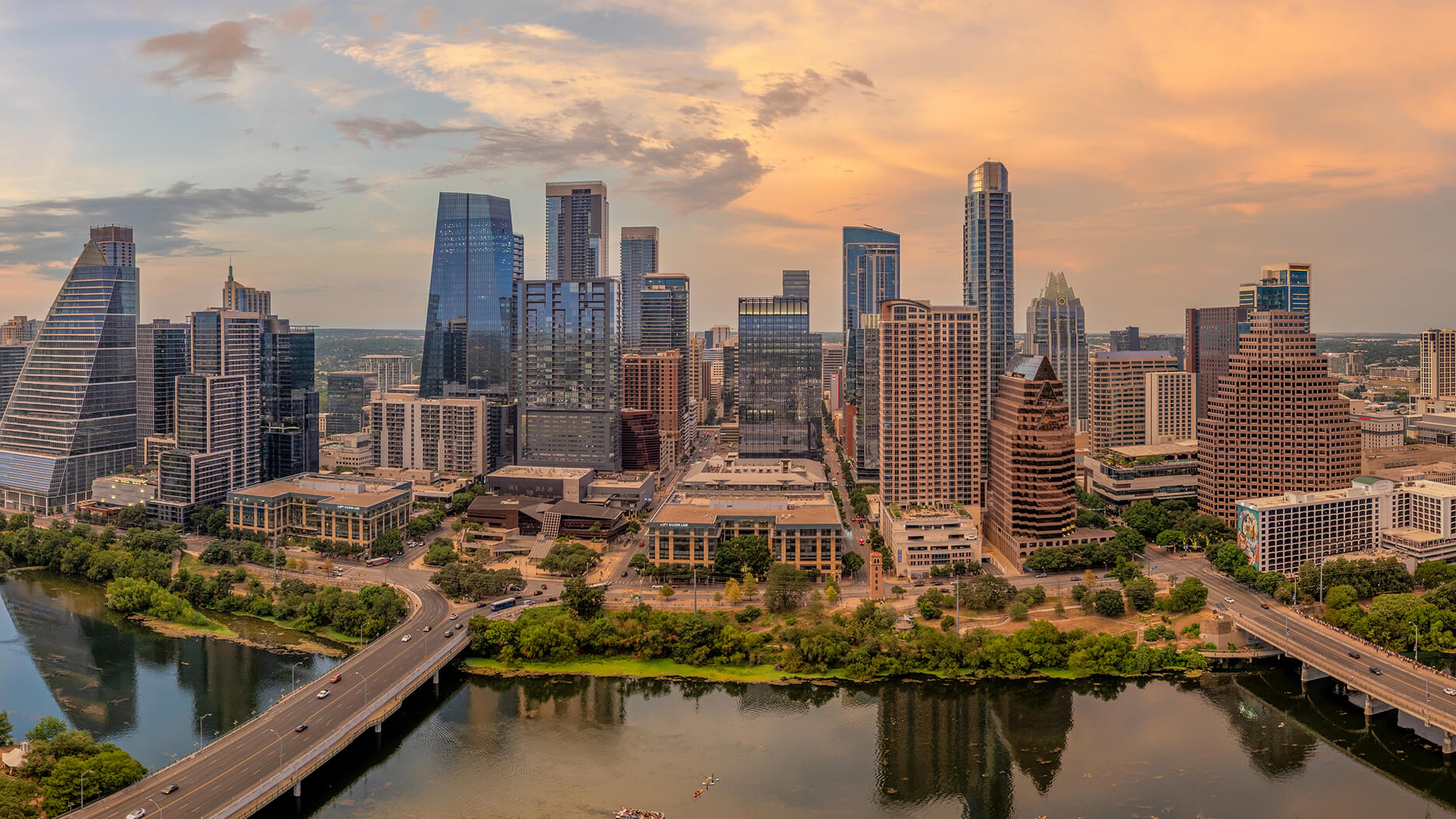 Aerial photograph of downtown Austin at sunset, with the skyline reflected in Lady Bird Lake