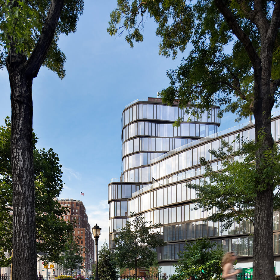 One Jackson Square in New York, a curved glass residential building on a tree-lined corner