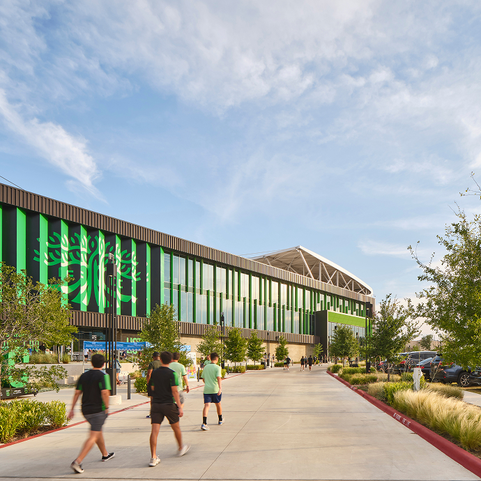 Q2 Stadium in Austin, its green façade fronted by a landscaped plaza with people walking past