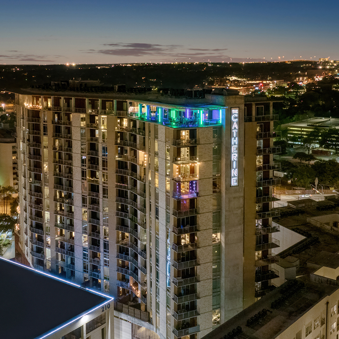The Catherine, a lit residential tower in Austin photographed at night against the city skyline