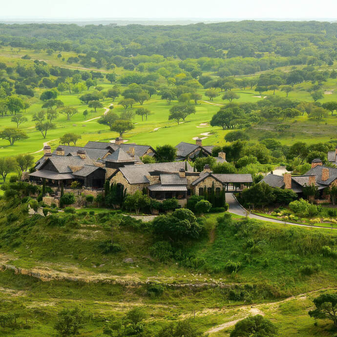 An aerial view of Boot Ranch in Fredericksburg, with stone buildings set among rolling green Hill Country