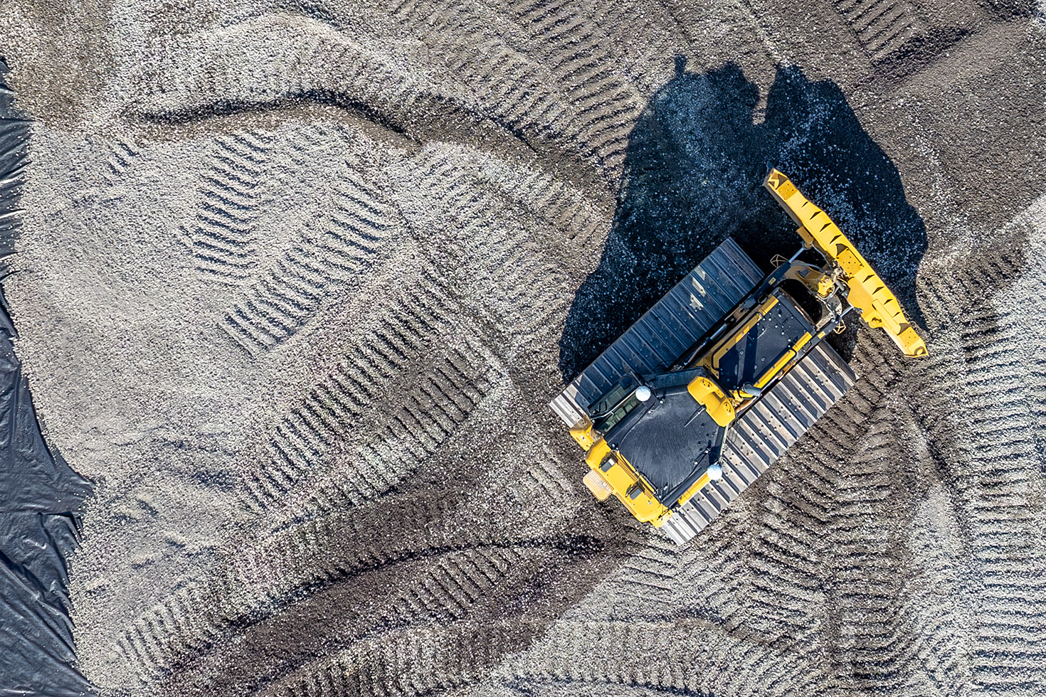 Aerial photograph of a bulldozer working across sheeting laid over the prepared construction site